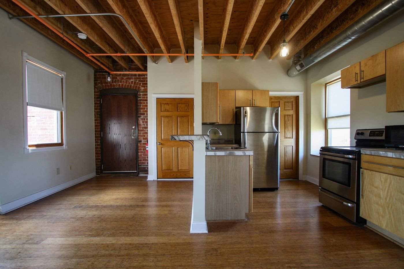 Loft interior with exposed wood joists, brick wall and kitchen island