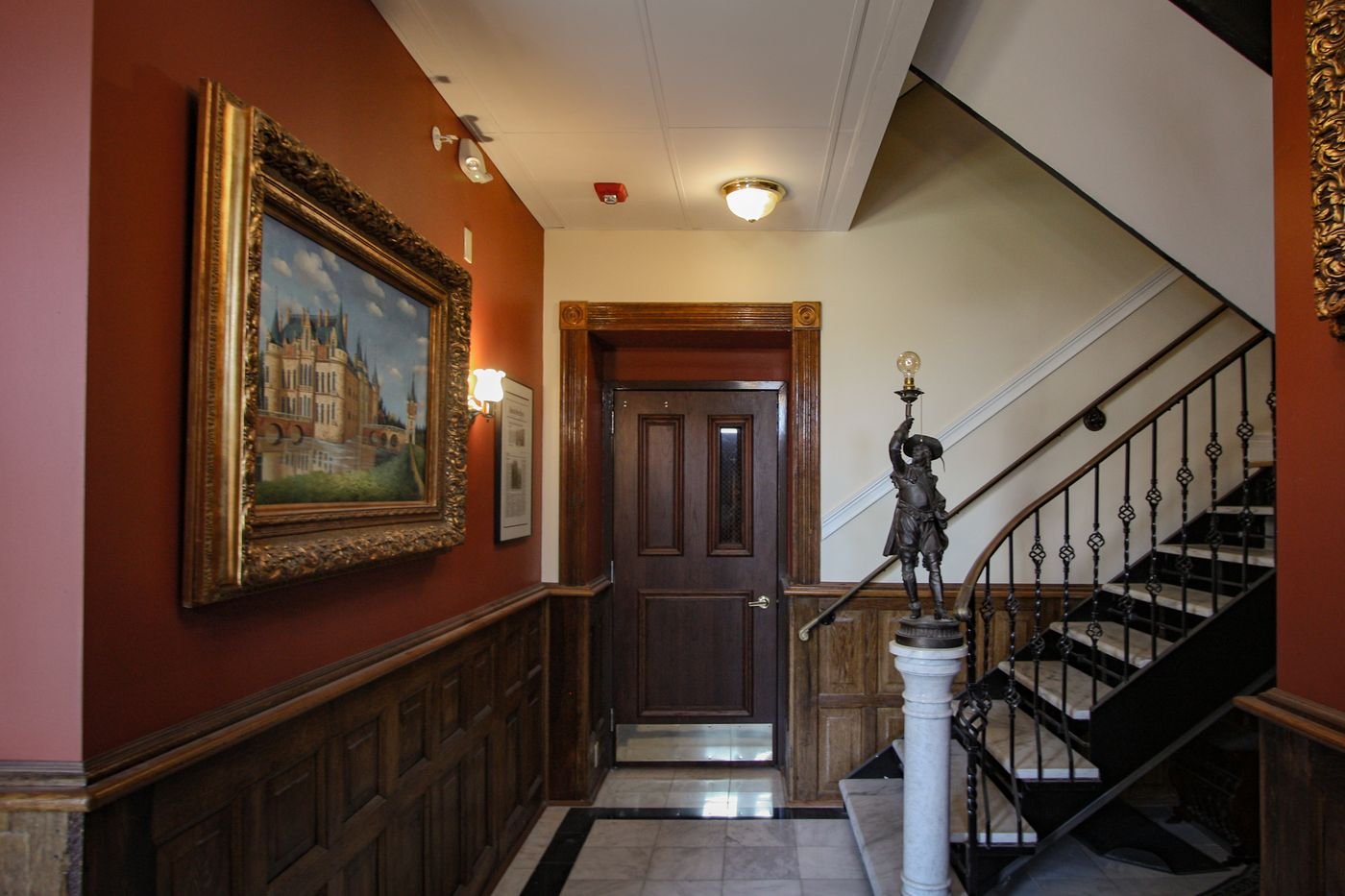 Entry hall with dark wood wainscoting and an iron stair
