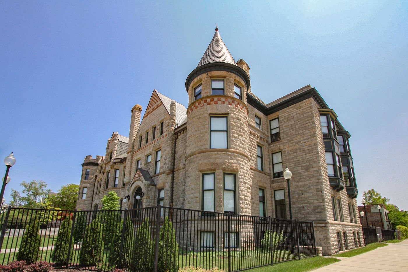 The James Scott Mansion: a sandstone house with a turret behind an iron fence